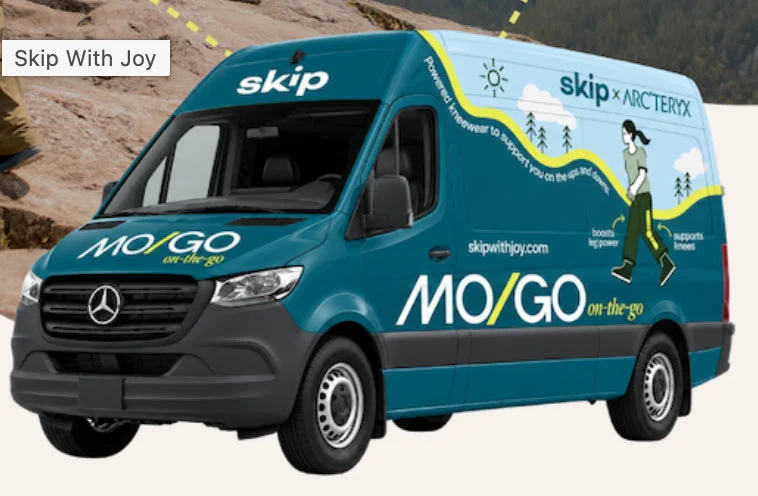 Skip MO/GO demonstration van with blue and green graphics.
